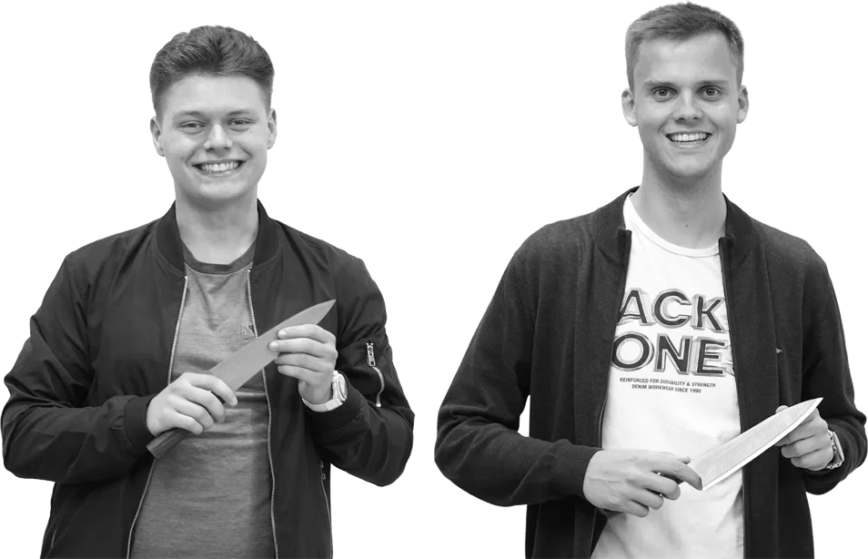 Zwei junge Männer, die lächelnd RYVON-Messer in der Hand halten und in die Kamera schauen, vor einem schlichten Hintergrund.